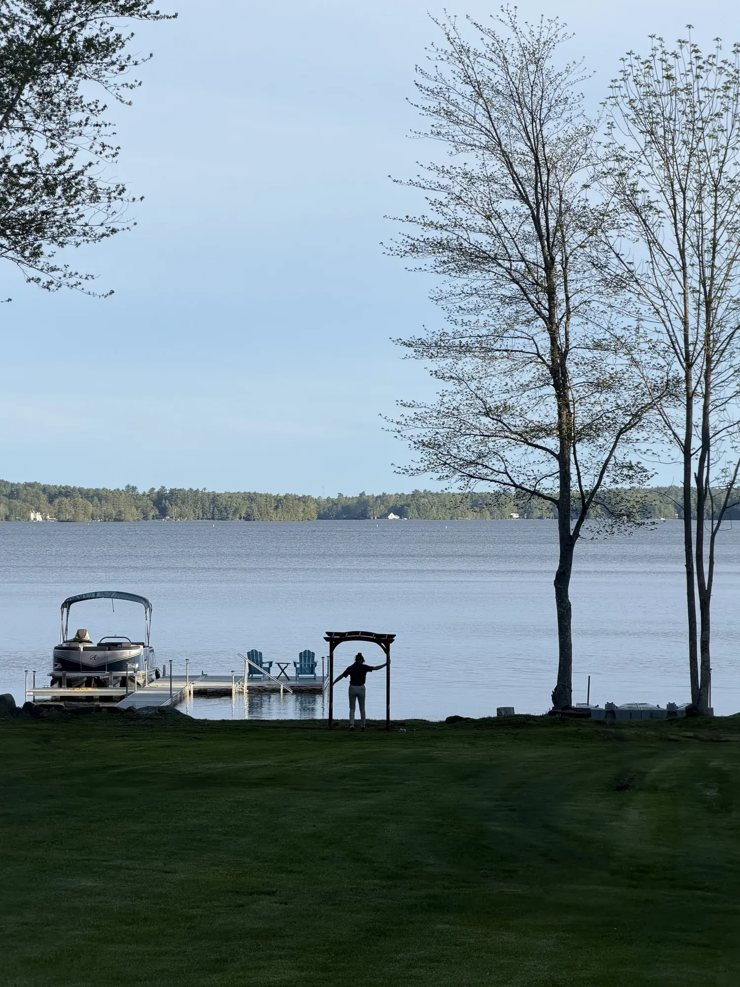 Lakeside wedding ceremony with an arbor and white chairs set up by Event Rent ME