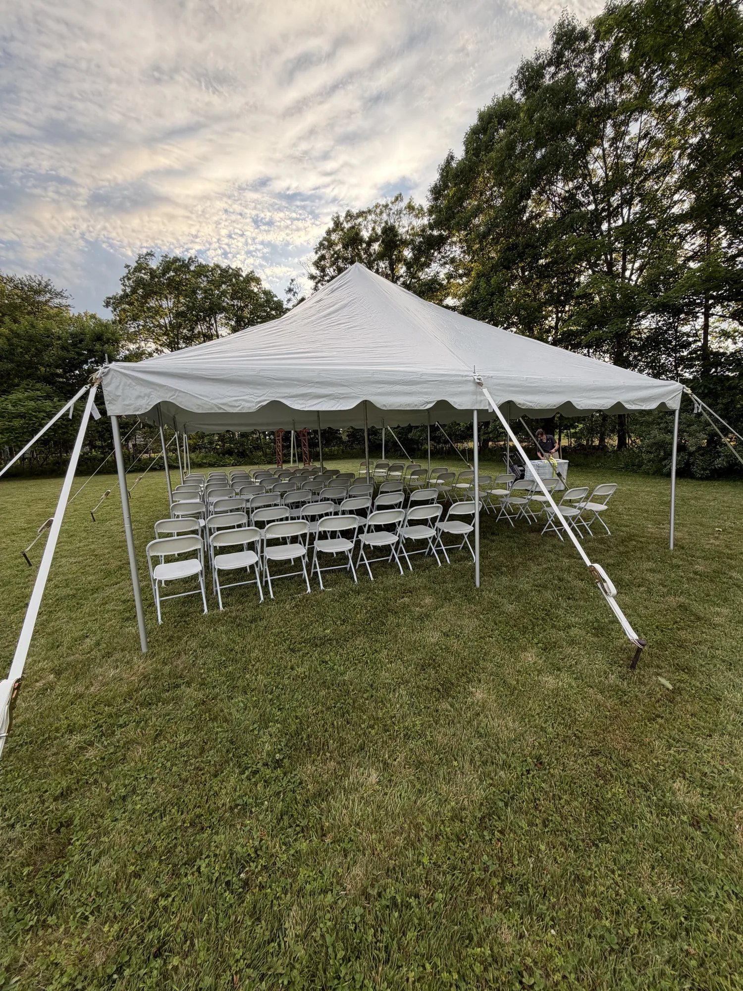White wedding ceremony chairs arranged beneath a tent